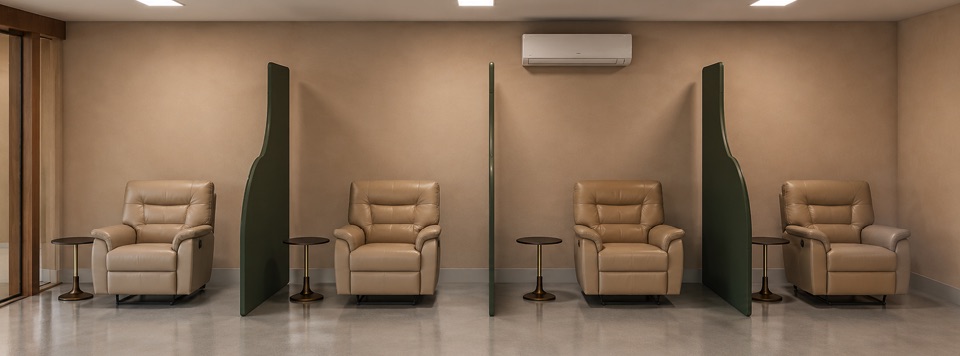 Quatro poltronas reclináveis de infusão separadas por divisórias verdes curvas